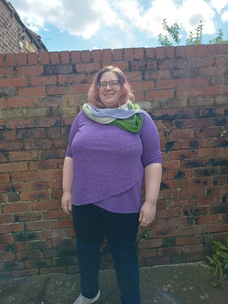 A photo of me wearing my Pronoun Party shawl, designed by Silver.